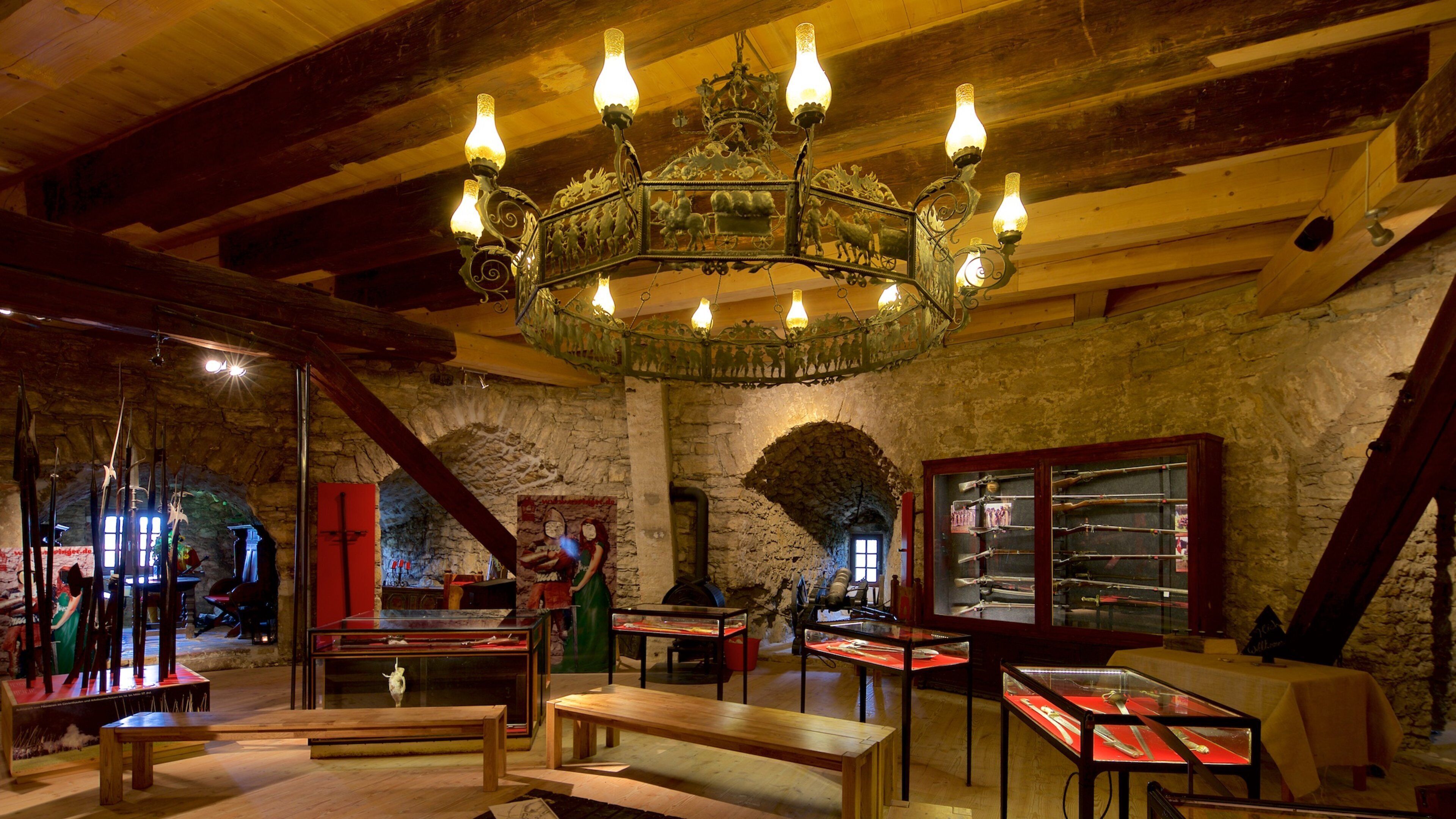 An interior with a wooden ceiling, stone walls, and a chandelier.