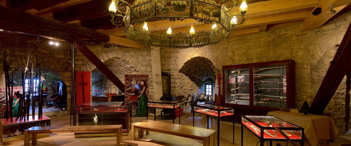 An interior with a wooden ceiling, stone walls, and a chandelier.