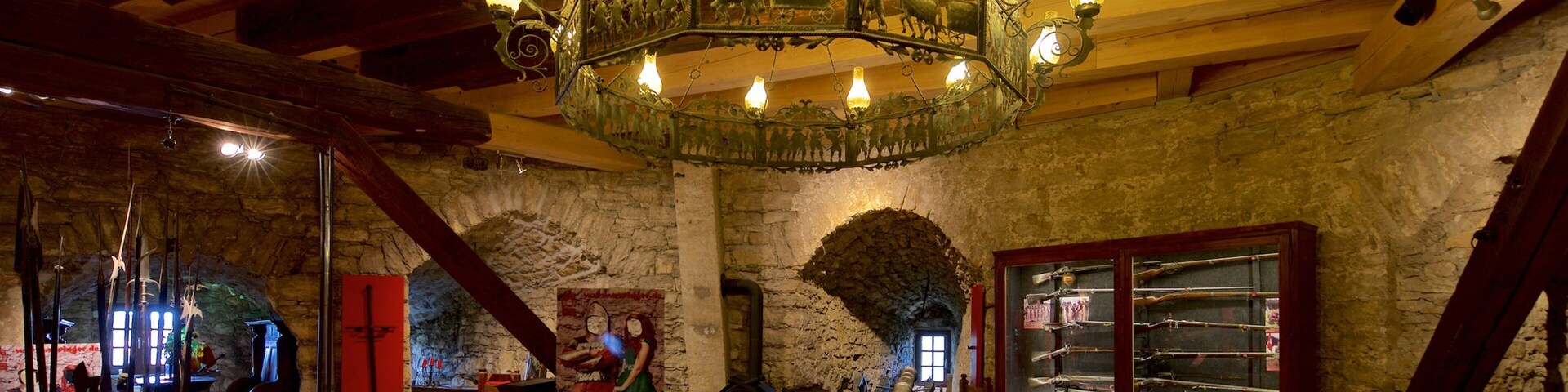 An interior with a wooden ceiling, stone walls, and a chandelier.
