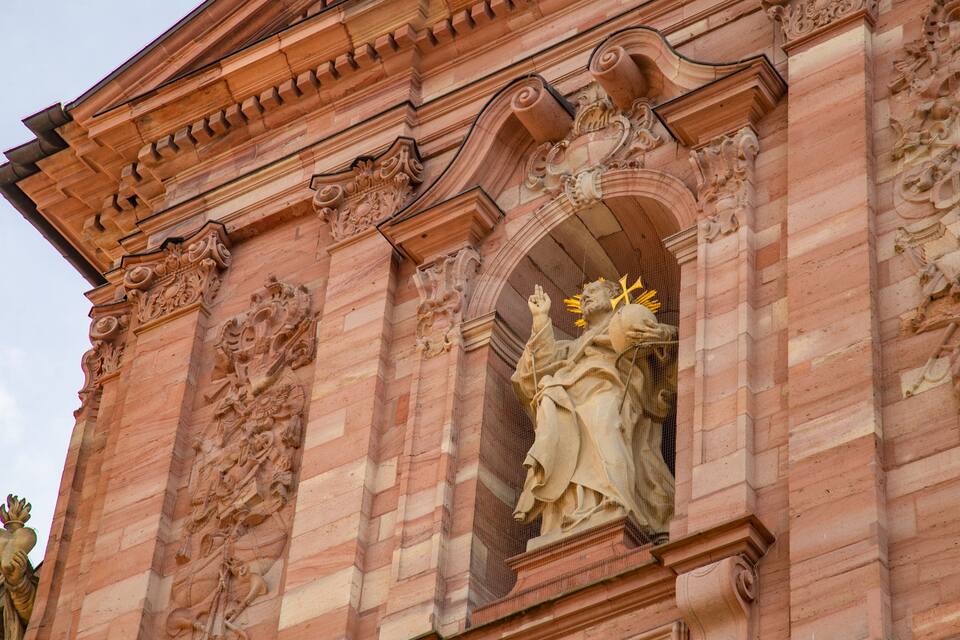 Een gedetailleerd gevelontwerp van een historisch pand met decoratieve snijwerk en beelden.