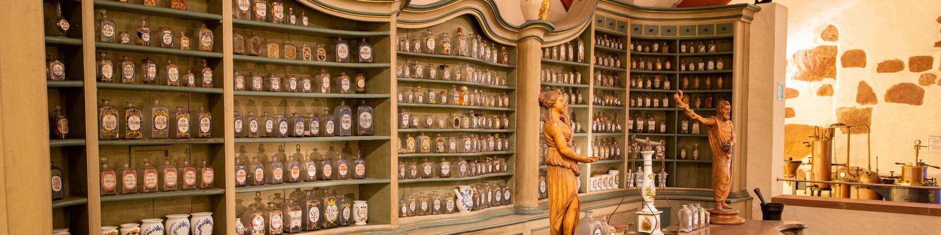A vintage apothecary with shelves of glass bottles and ceramic containers.