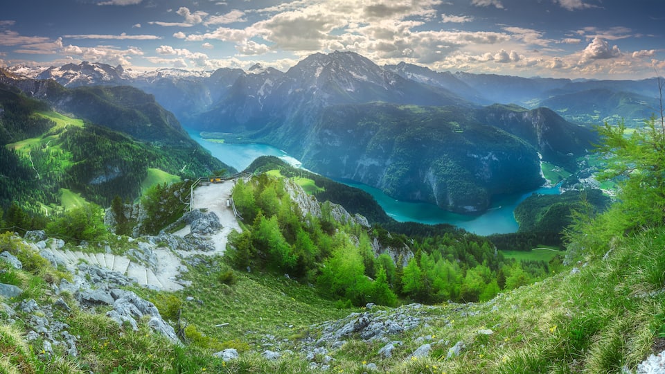 A mountainous landscape with a turquoise lake surrounded by lush greenery and rocky terrain.