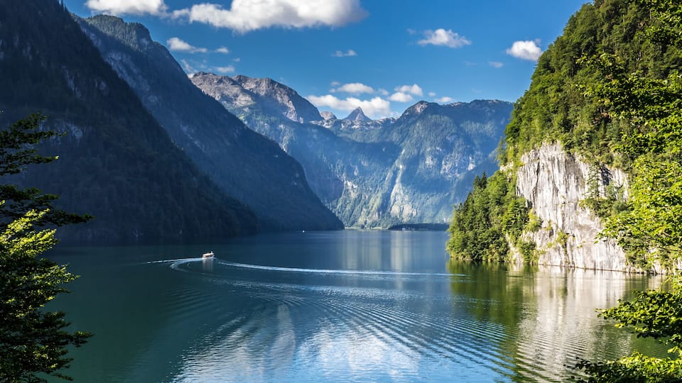 A calm lake surrounded by steep mountains and dense forests.