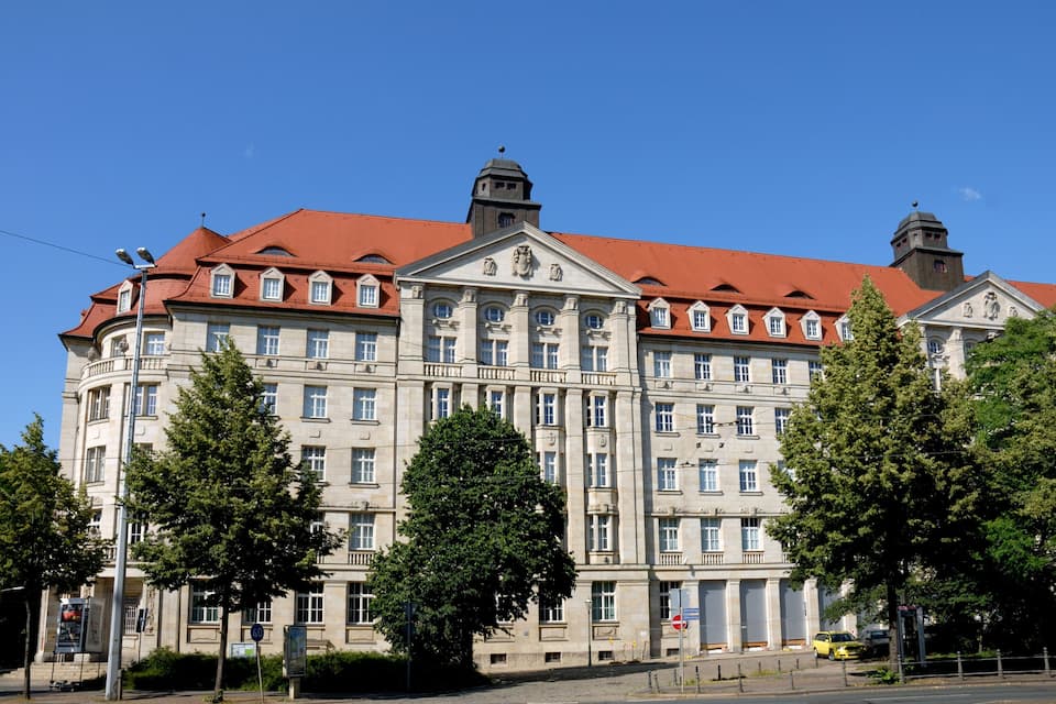 Un grand bâtiment historique doté d’un toit rouge et de nombreuses fenêtres.
