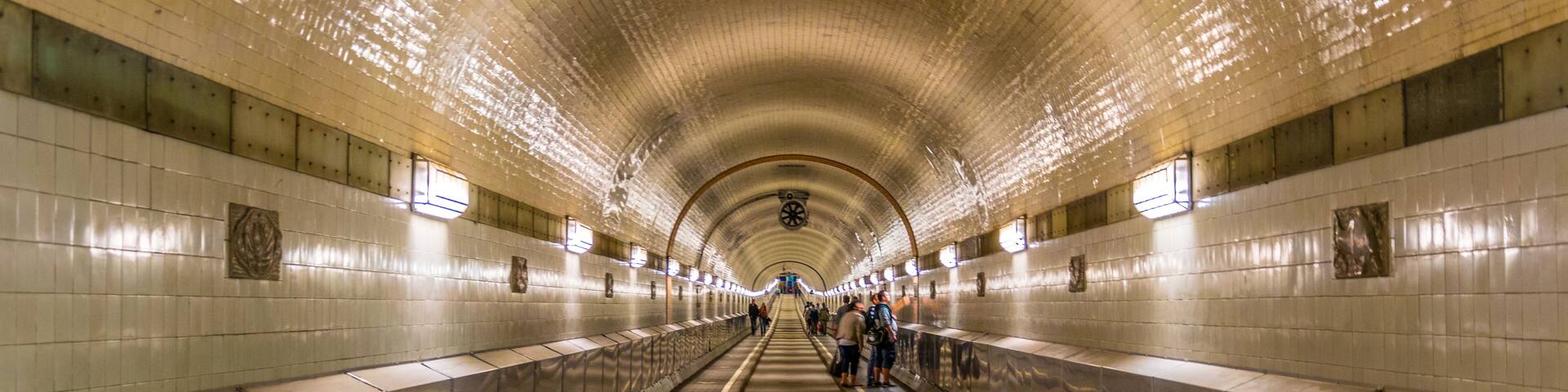 Una estación de metro con paredes de azulejos, techo curvo y pasillo central.