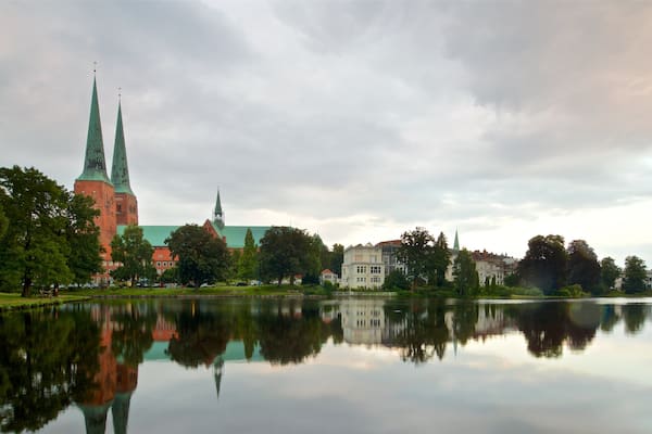 Un lac paisible où se reflète une église à deux flèches, entourée de verdure.