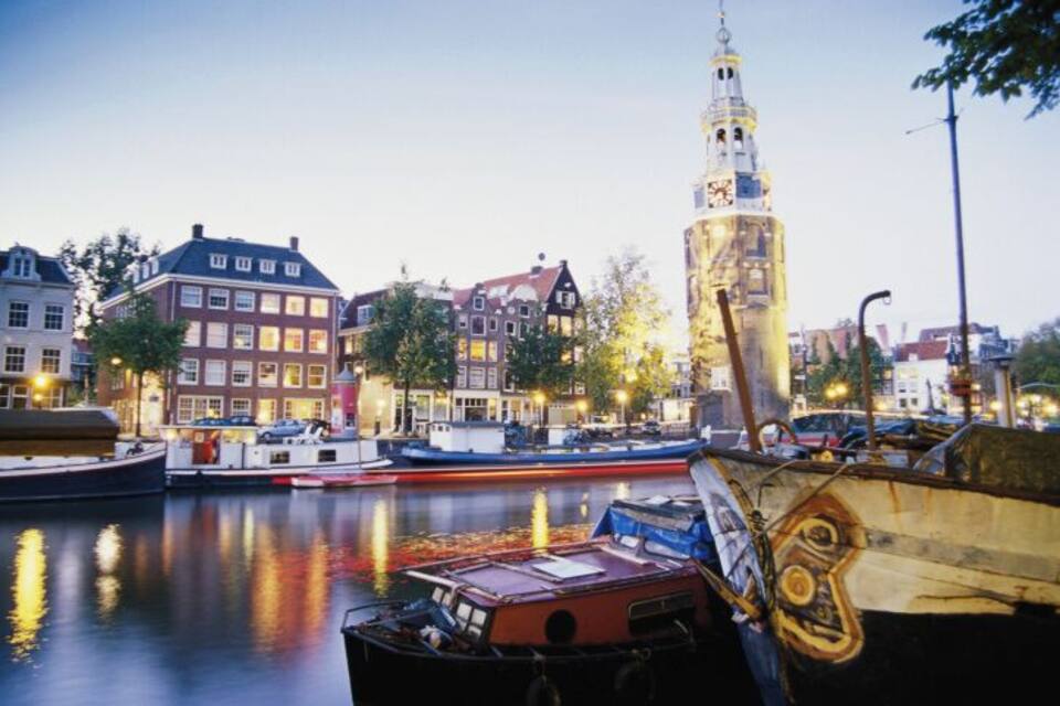 A canal with boats, historic buildings, and a prominent tower.