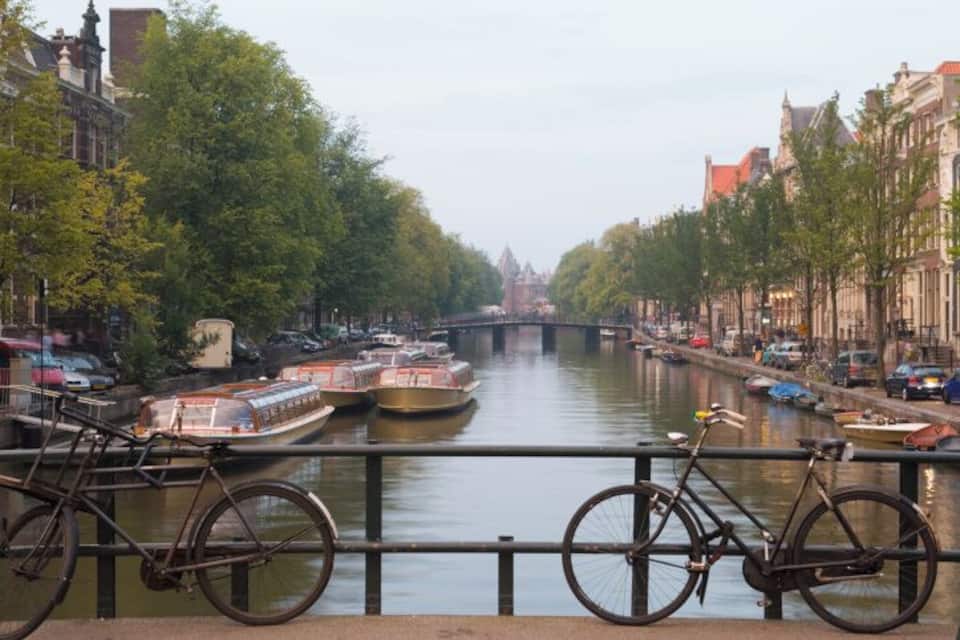 A canal with boats, bicycles, and historic buildings along the water's edge.
