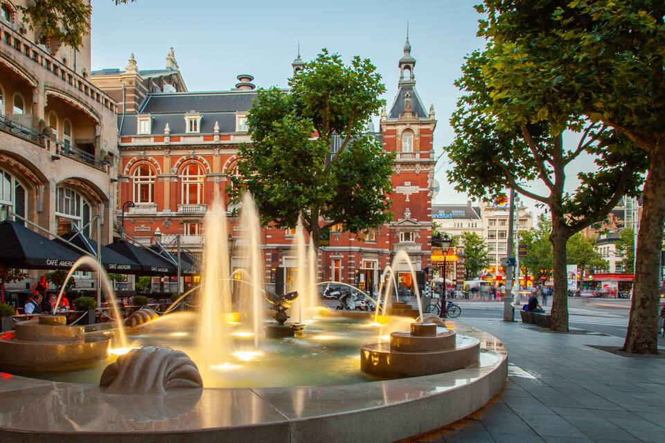 A public square with a fountain, cafes, and historic buildings.