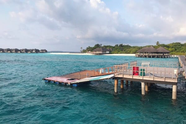 A pier extending into turquoise waters with a small boat docked at the end.