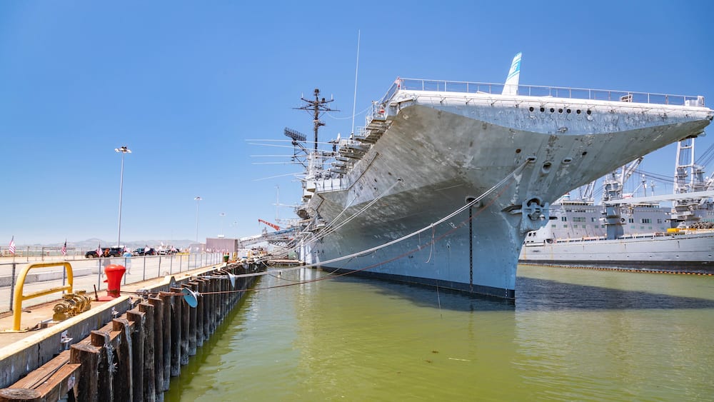 A large ship docked at a pier with a clear sky.