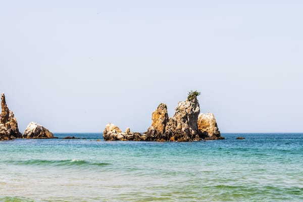 A coastal landscape with rocky formations and clear blue water.