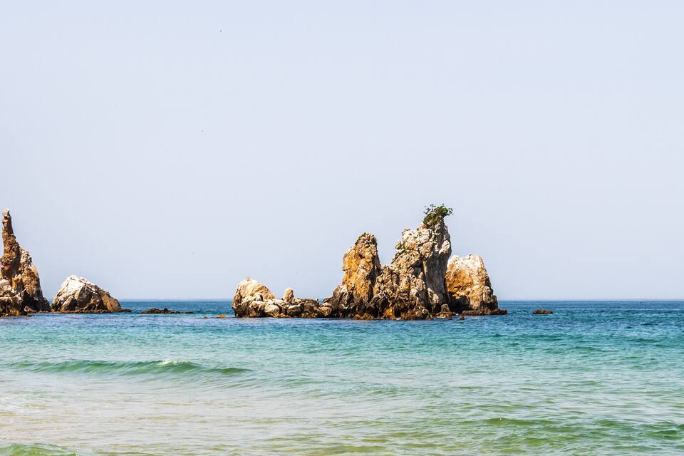 Paesaggio costiero con formazioni rocciose e acqua cristallina.