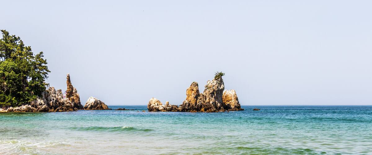 A coastal landscape with rocky formations and clear blue water.
