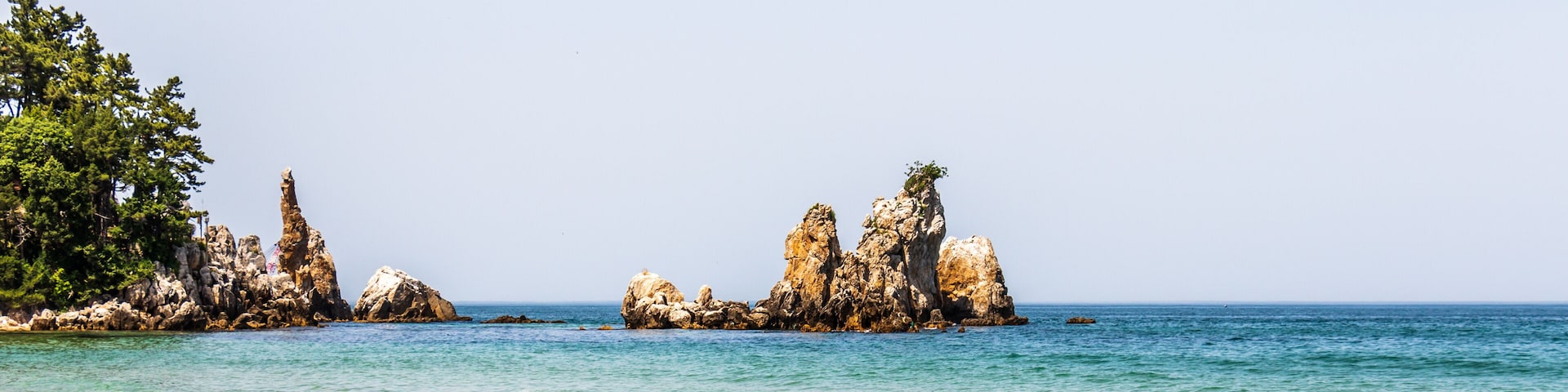 A coastal landscape with rocky formations and clear blue water.