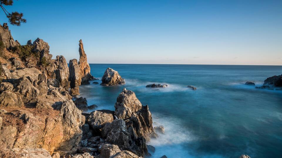 A rocky coastline with prominent rock formations and a calm sea.
