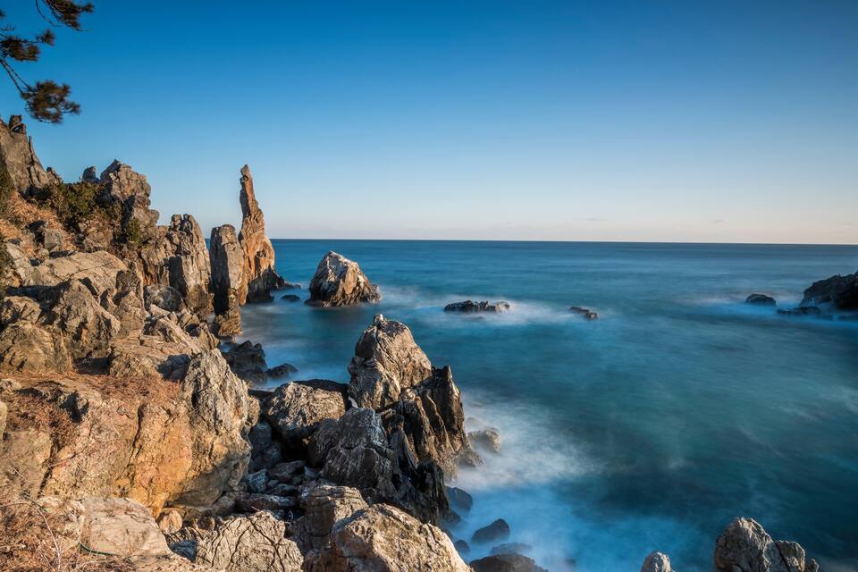A rocky coastline with prominent rock formations and a calm sea.
