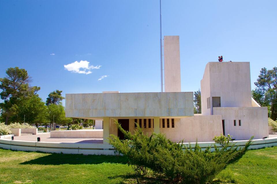 A modern architectural building with a tall central tower and a circular plaza with benches.