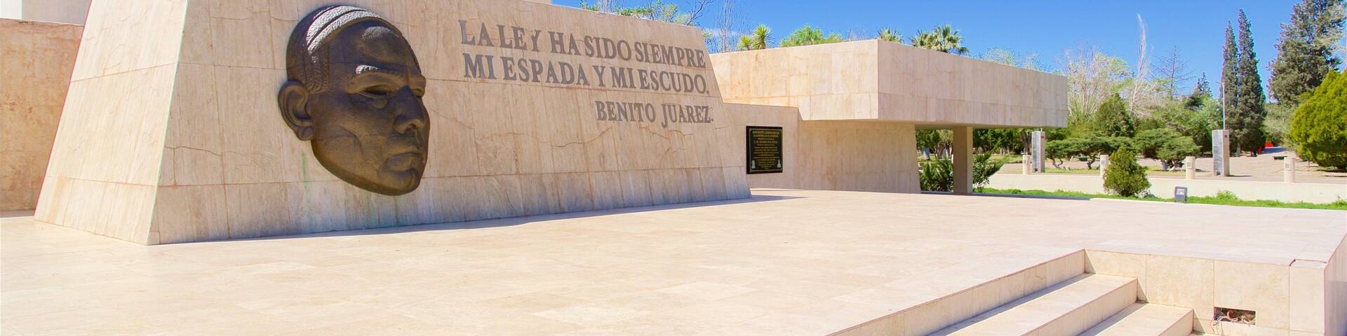 A monument with a carved head and a plaque with text.