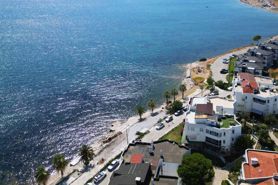 A coastal residential area with buildings, a beach, and a clear blue sea.