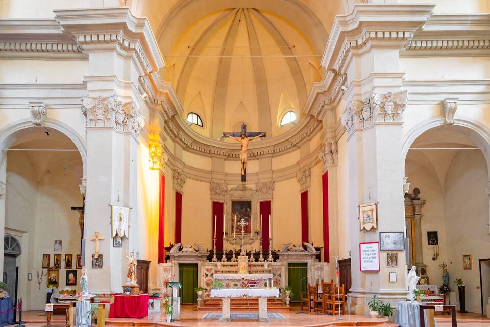 An ornate church interior with a crucifix, altar, and religious statues.