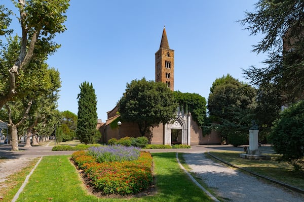 Une église dotée d’un haut clocher, entourée de jardins et d’arbres bien entretenus.