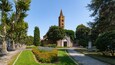A church with a tall bell tower, surrounded by well-maintained gardens and trees.