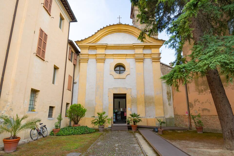 A courtyard with a building featuring a yellow facade and a central archway.