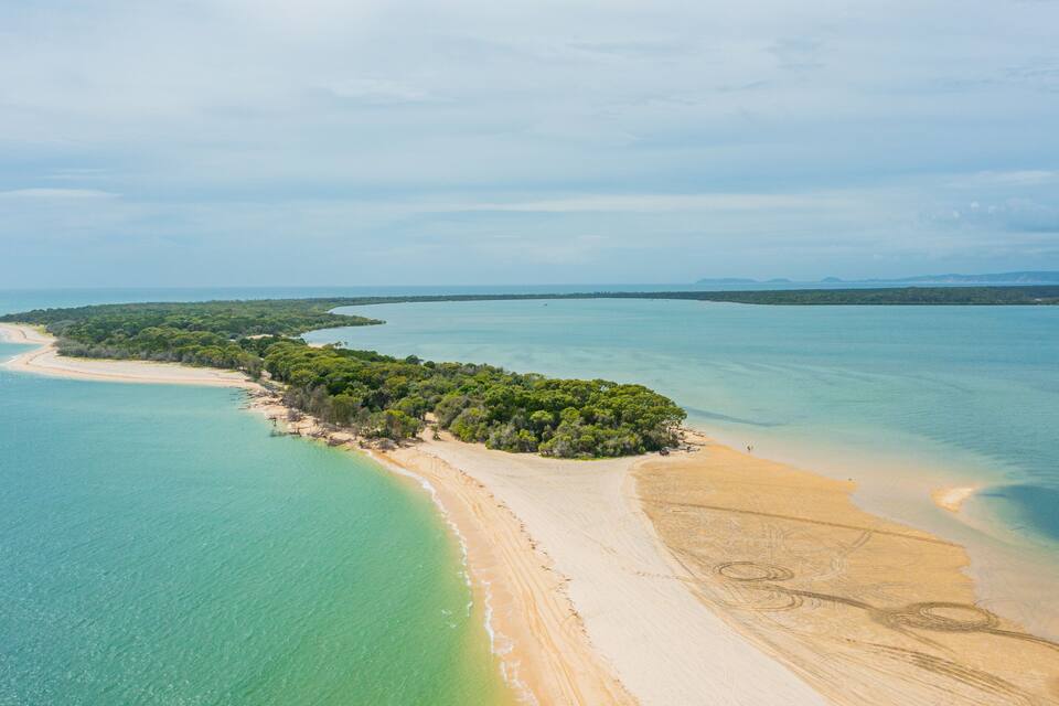 Vista aèria d'una illa tropical amb aigües turqueses cristal·lines, platges sorrenques i vegetació verda densa.
