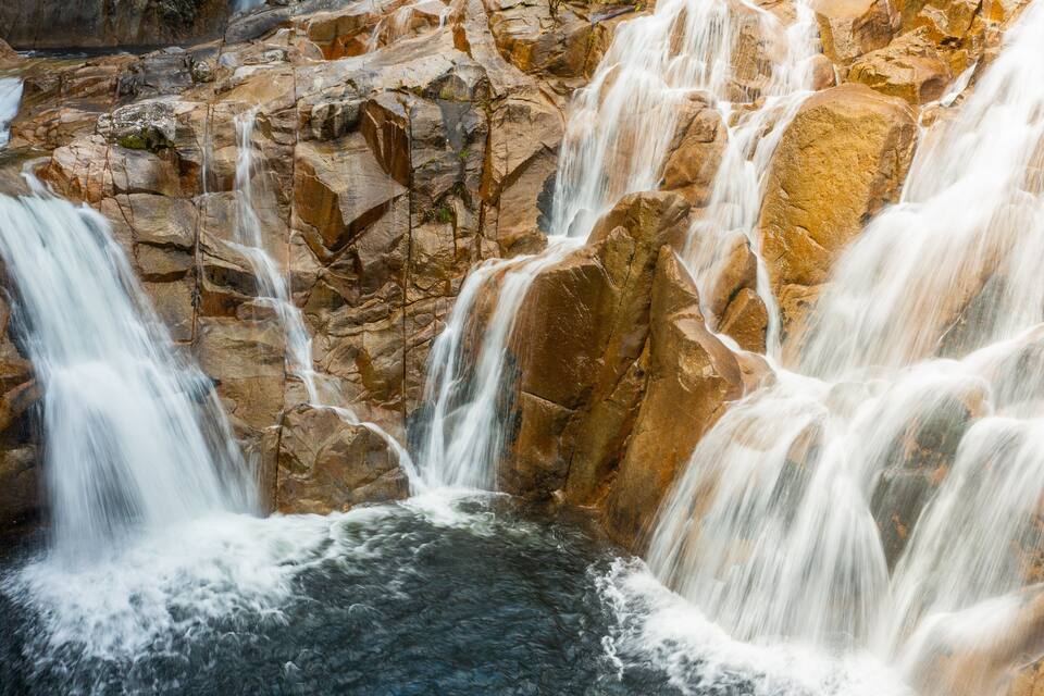 Una cascada en terrasses que flueix sobre un terreny rocos.
