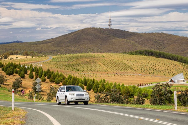 A white SUV driving on a road with a mountainous landscape in the background.