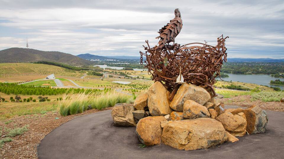 A sculpture of a bird on rocks with a scenic landscape in the background.