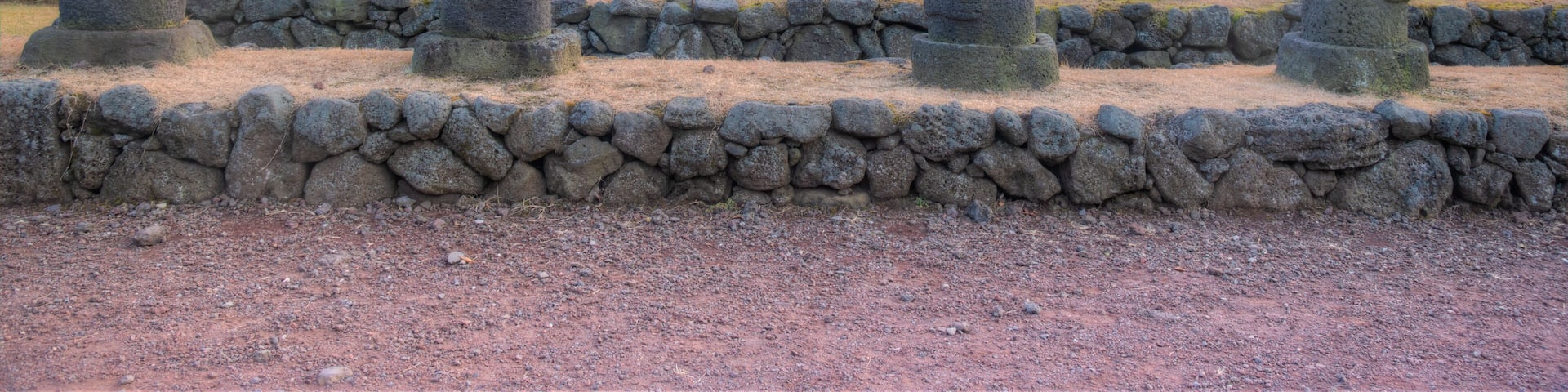 A row of standing stone statues in a natural landscape.