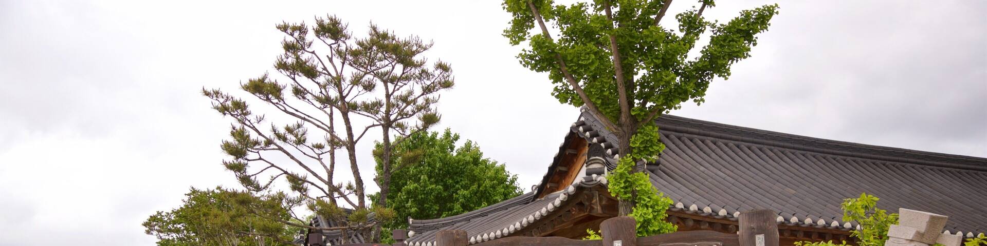 A traditional Korean village entrance with wooden signage and a stone pathway.