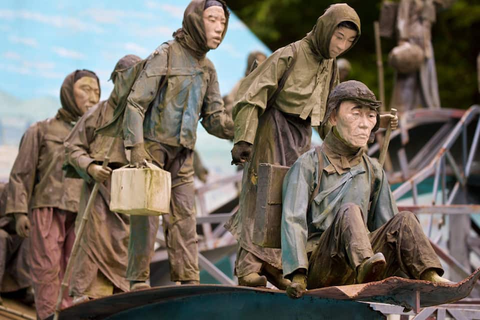 Un grupo de soldados uniformados, algunos de pie y otros sentados, con un bote en primer plano.