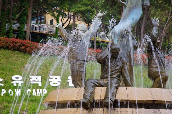 A sculpture of a man sitting on a stone platform with water flowing from his hands.