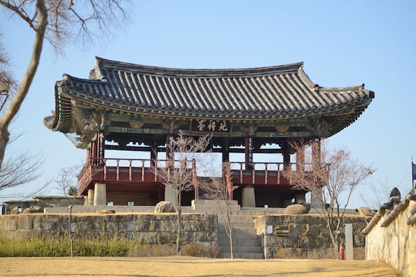 A traditional Korean pavilion with ornate roof tiles and a stone base.