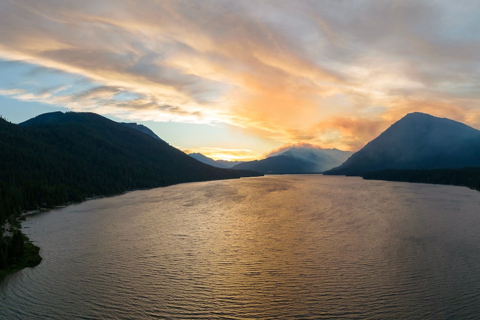 Ein stiller See, umgeben von Bergen im Abendlicht.