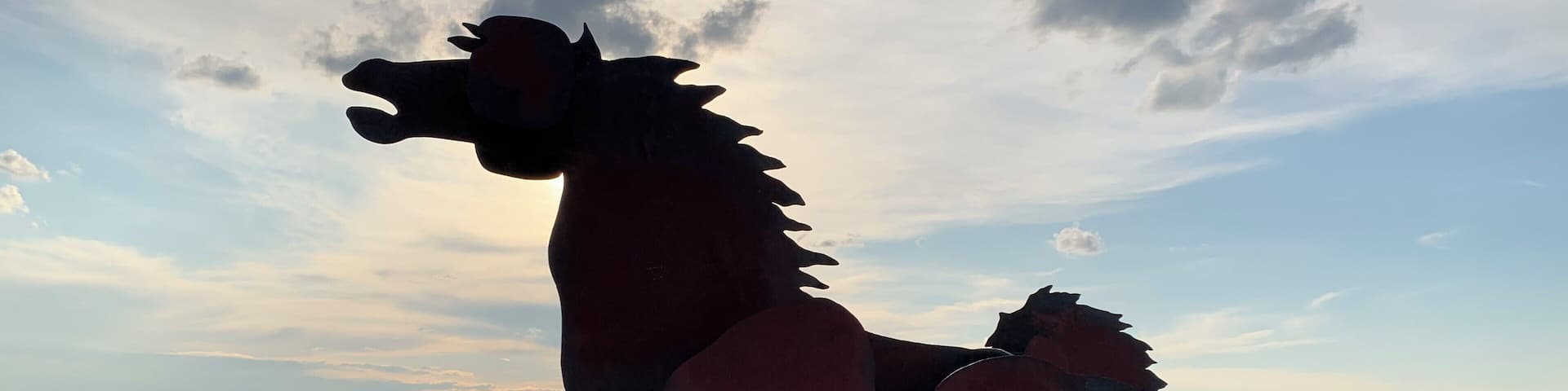 Una escultura de metal de un caballo en un paisaje desértico con montañas a lo lejos.
