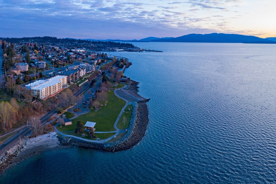 A coastal town with a harbor, residential buildings, and a mountainous backdrop.