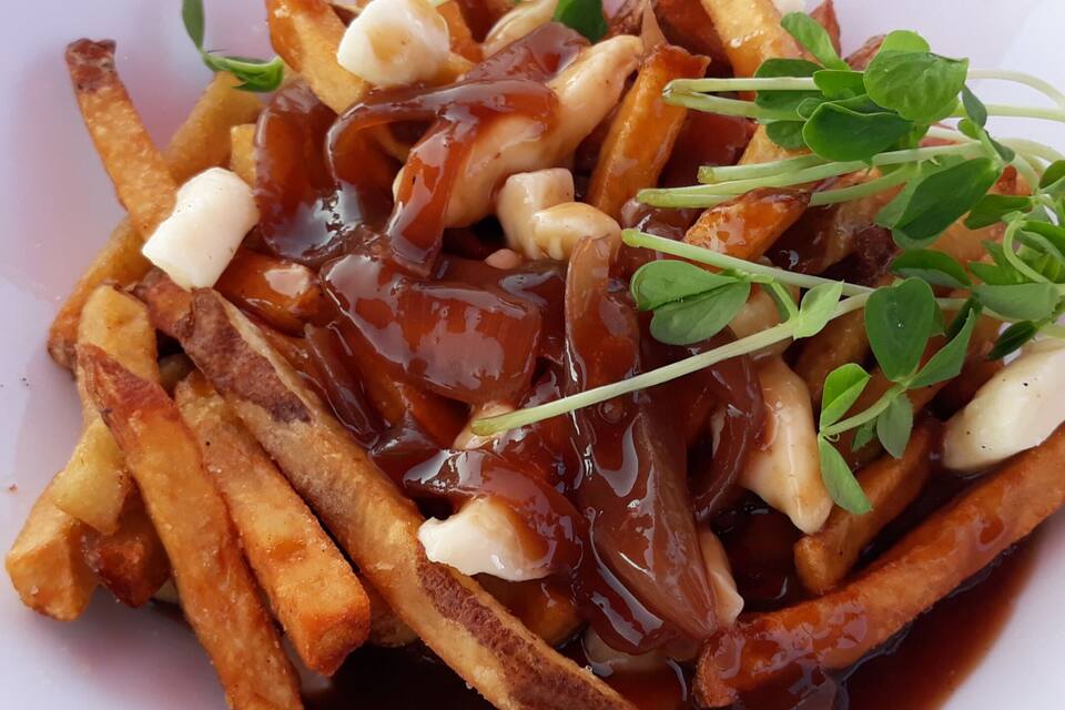 Un plato de patatas fritas, queso a la quejada y salsa gravy.