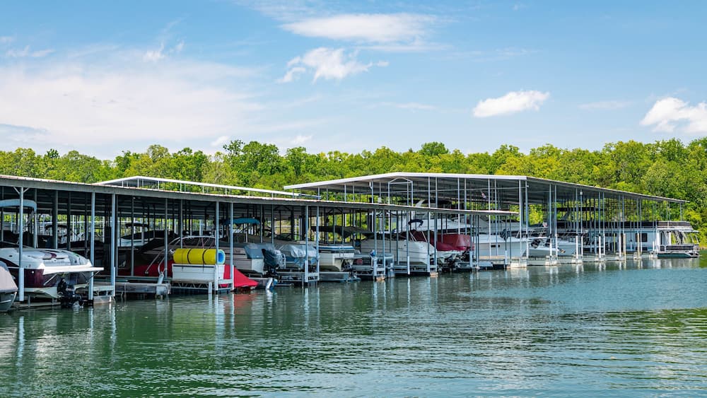 A marina with several boats docked under covered structures.