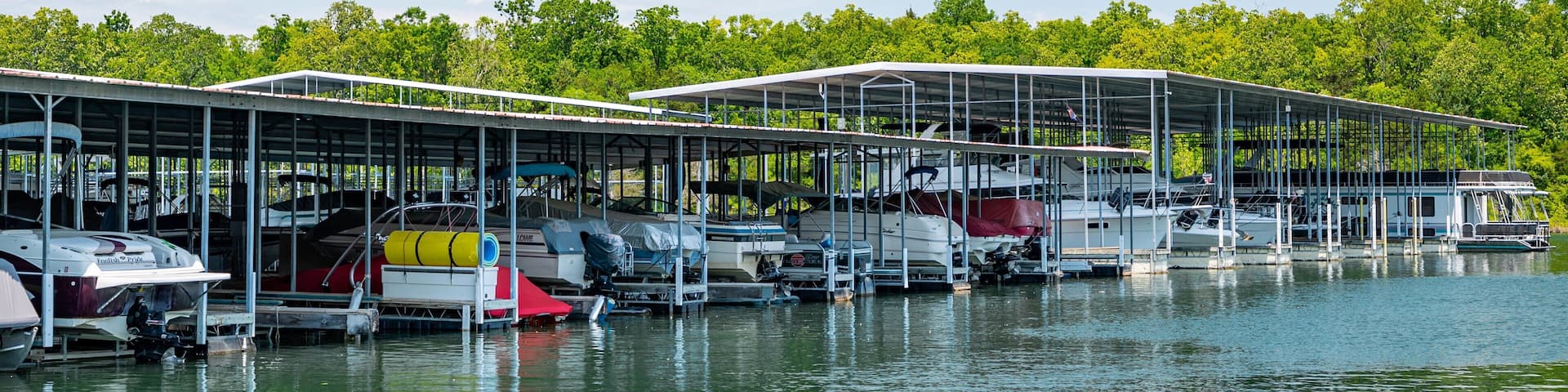 A marina with several boats docked under covered structures.