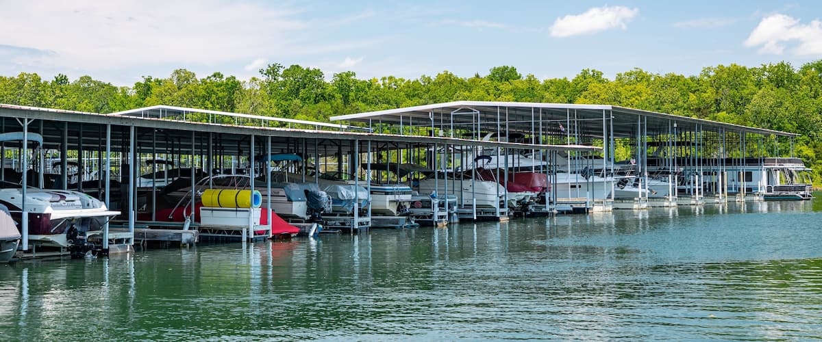 A marina with several boats docked under covered structures.