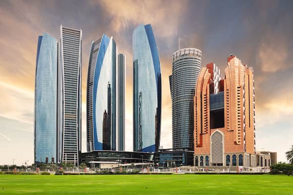 A modern cityscape with skyscrapers, a Grand Hyatt hotel, and a mosque with intricate architecture.