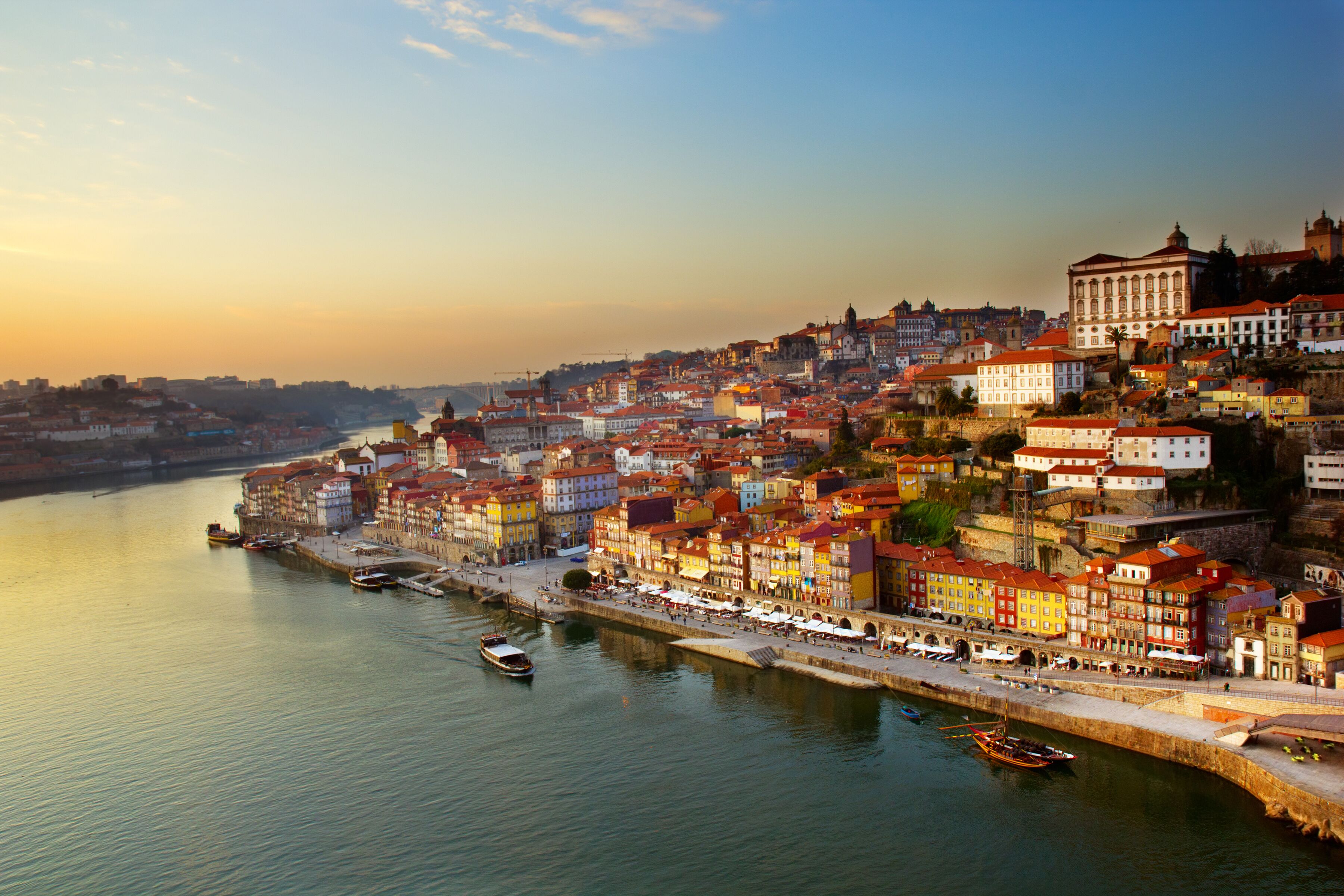 A riverside cityscape with colorful buildings and boats.
