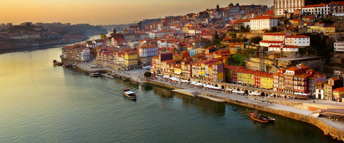 A riverside cityscape with colorful buildings and boats.
