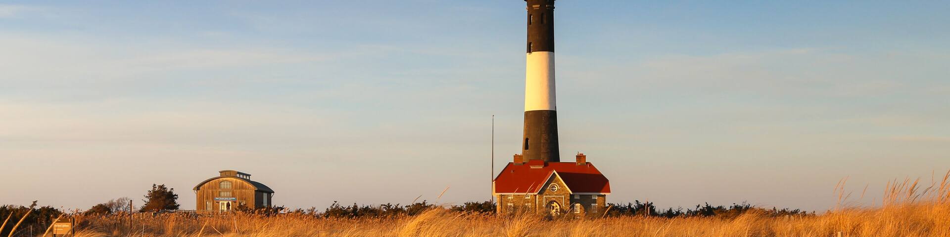 Scenic Fire Island Lighthouse with beach, dunes, dune grasses in late afternoon light.