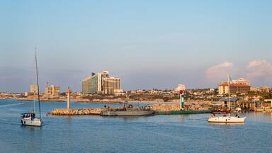 A harbor with boats, a lighthouse, and a cityscape with buildings.