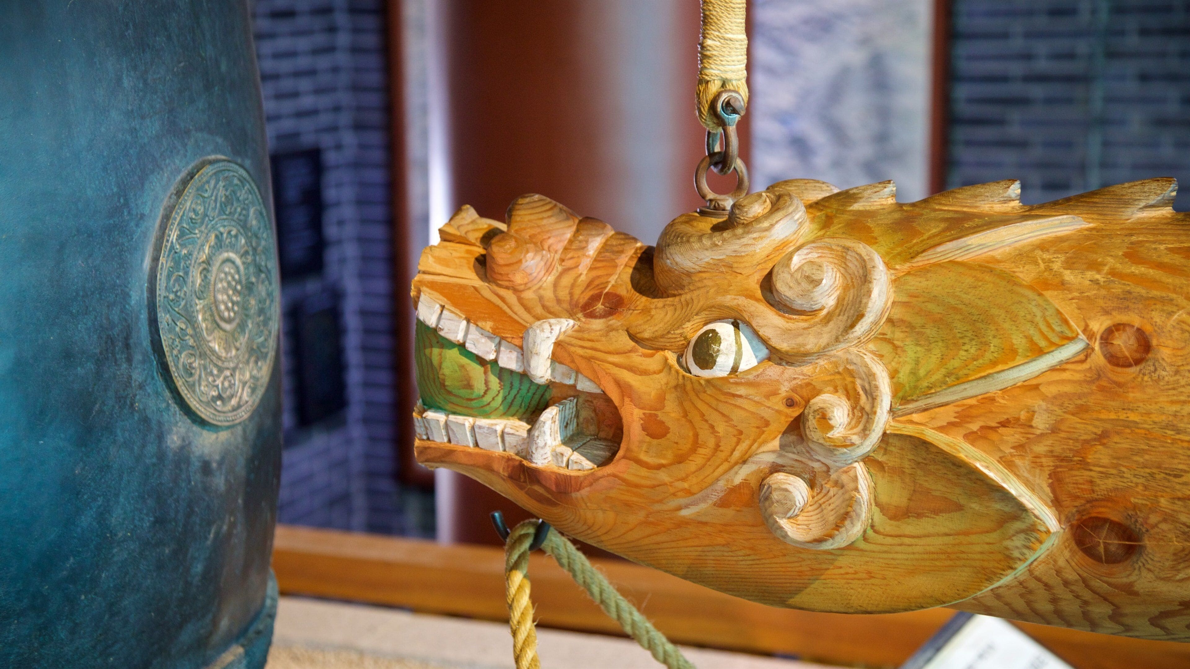 Una detallada escultura de madera con expresión intensa, con tallas intrincadas y una cuerda atada a ella.